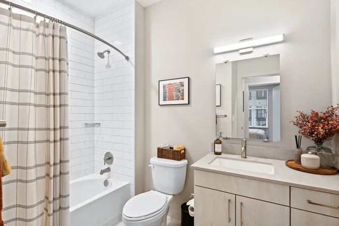 A modern bathroom with a sleek shower, a toilet, and a sink at Lofts at Yard 56.