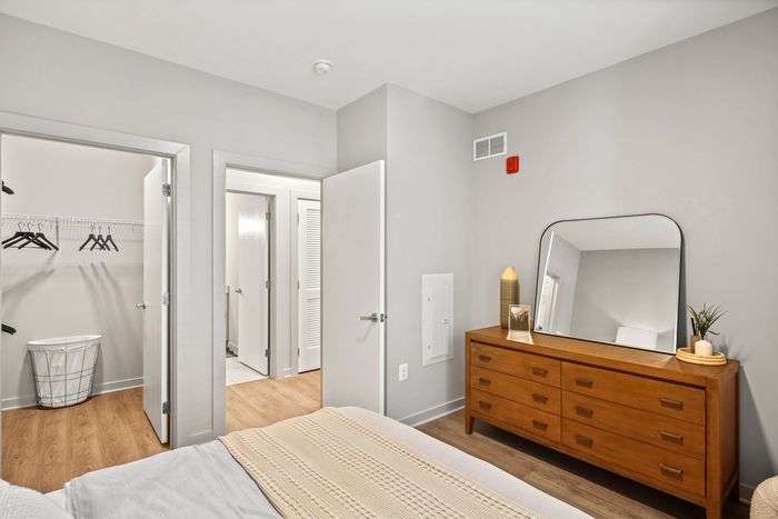 Lofts at Yard 56 bedroom with a comfortable bed, a stylish dresser, and a mirror for getting ready.