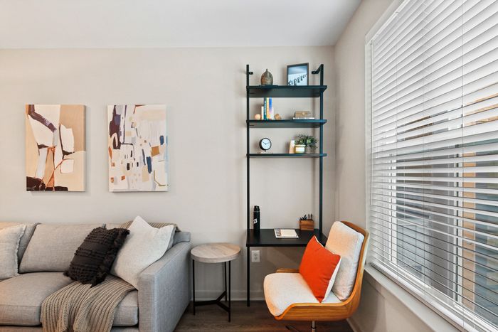 Lofts at Yard 56 living room with a comfy couch, a stylish chair, and a sleek shelf for displaying decor.