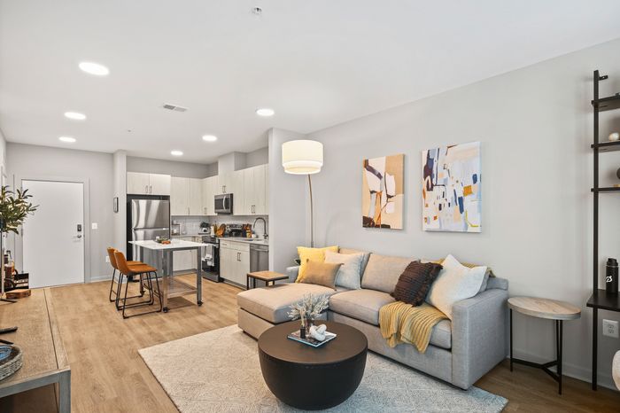 Spacious living room with a comfy couch, sleek coffee table, and a glimpse of the kitchen at Lofts at Yard 56.