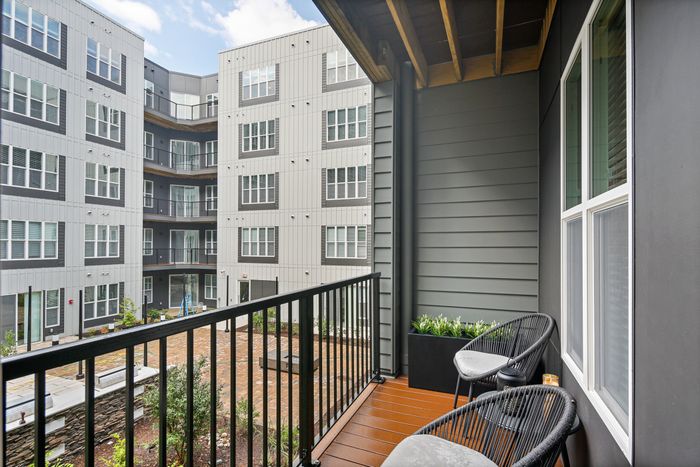 Outdoor balcony with two chairs and a table overlooking a scenic view at Lofts at Yard 56.