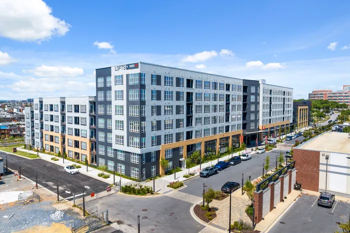 Yard 56 Lofts building in Baltimore on a street corner, surrounded by trees and parked cars..