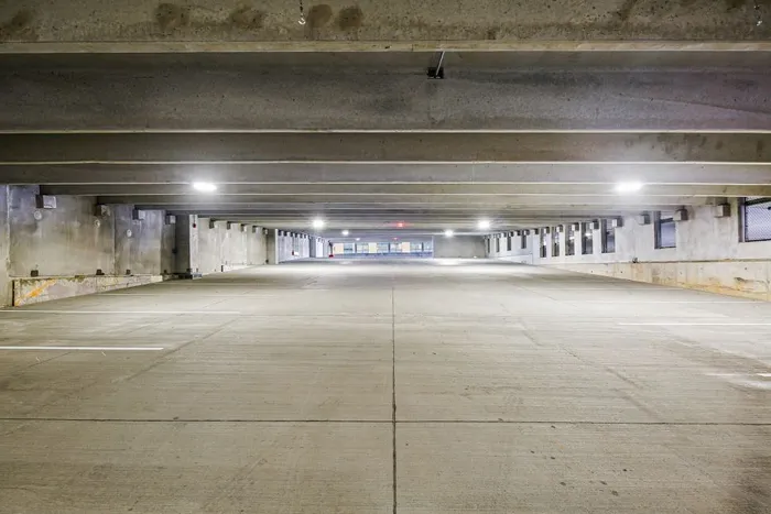 Spacious, brightly lit parking garage at Lofts at Yard 56 with empty spaces and illuminated overhead lights.
