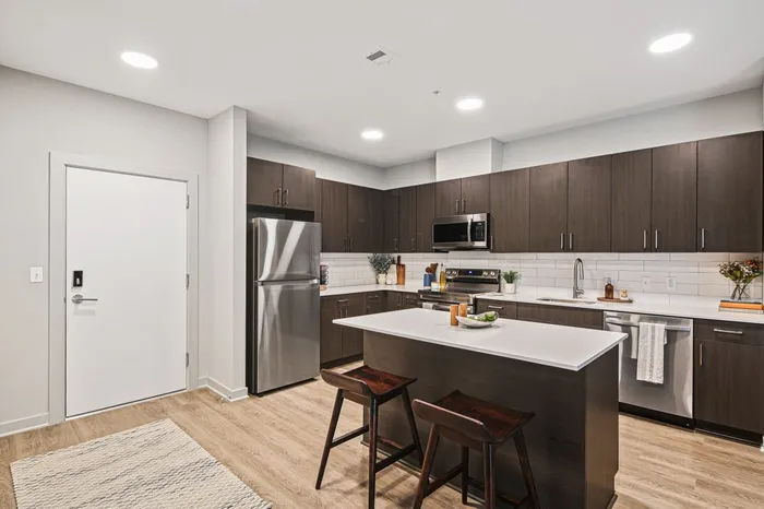 Modern kitchen with stainless steel appliances and warm wood floors in a two-bedroom at Lofts at Yard 56.