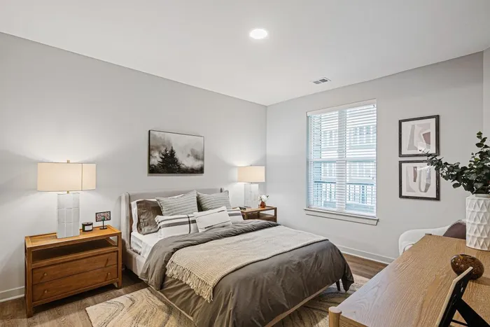 A serene bedroom with a comfortable bed, a workspace desk, and a window for fresh air and sunlight at Lofts at Yard 56.