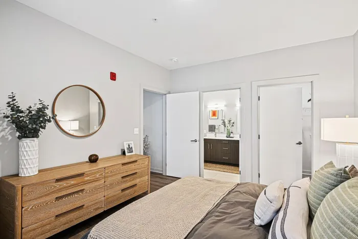 Peaceful bedroom with bed, contemporary dresser, and mirror brightening the space at Lofts at Yard 56.