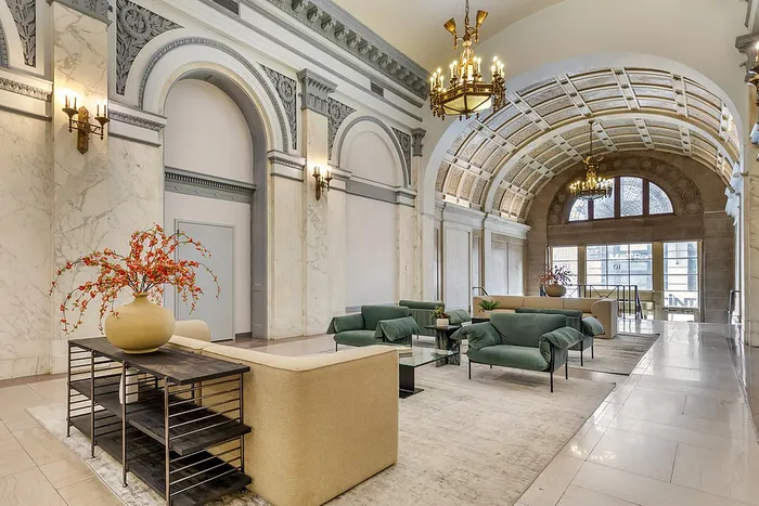 Elegant apartment lobby with marble accents, ornate chandeliers, and plush seating.