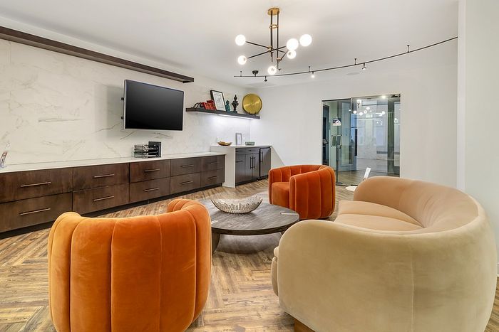 Contemporary clubhouse with stylish orange and beige seating, elegant lighting, and sleek media unit.