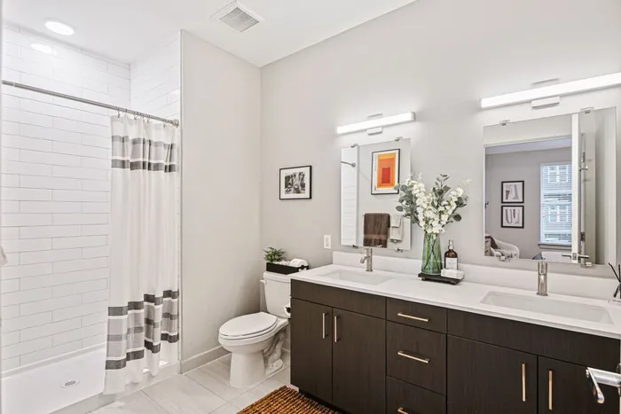 A well-designed bathroom at Lofts at Yard 56, showcasing a shower, toilet, and sink for convenient living.