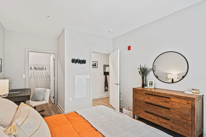 Cozy bedroom at Lofts at Yard 56 featuring a bed, dresser, and mirror for a stylish living space.
