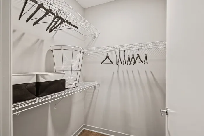A tidy walk-in closet featuring neatly arranged clothes and baskets at Lofts at Yard 56 two-bedroom model.
