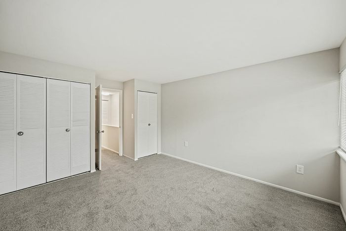Bright and spacious bedroom featuring plush carpeting, two closets, and ample natural light.