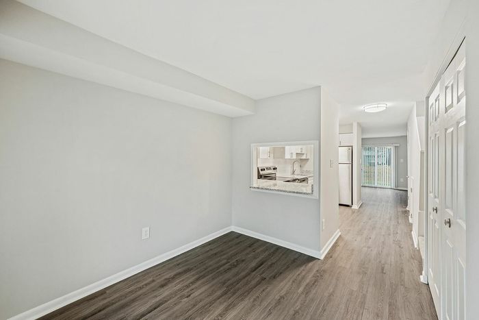 Bright and spacious apartment hallway with a view of a sleek kitchen and sliding doors leading to a backyard.