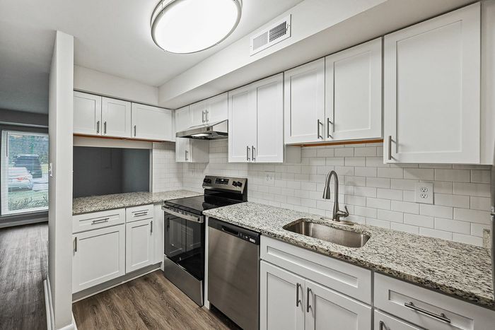 Sleek contemporary kitchen with granite countertops and white cabinetry.