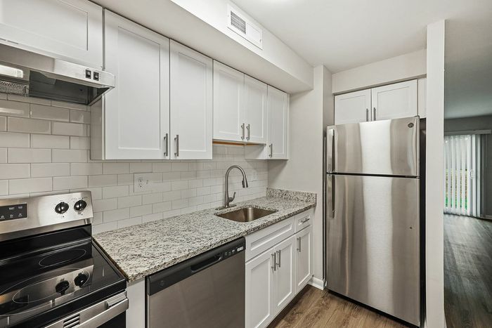 Sleek modern kitchen with stainless steel appliances, granite countertops, and white cabinetry.