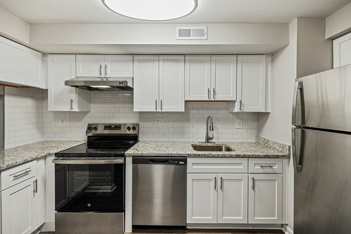 Contemporary kitchen with stainless steel appliances, granite countertops, and white cabinetry.