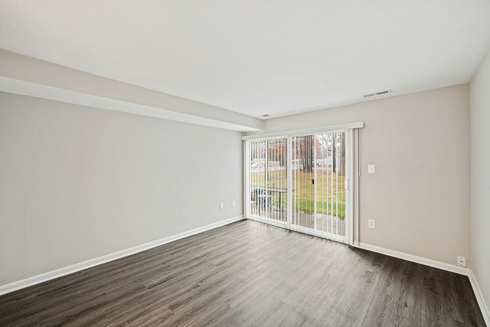 Spacious living room with sleek hardwood floors and large sliding glass doors leading to a patio.