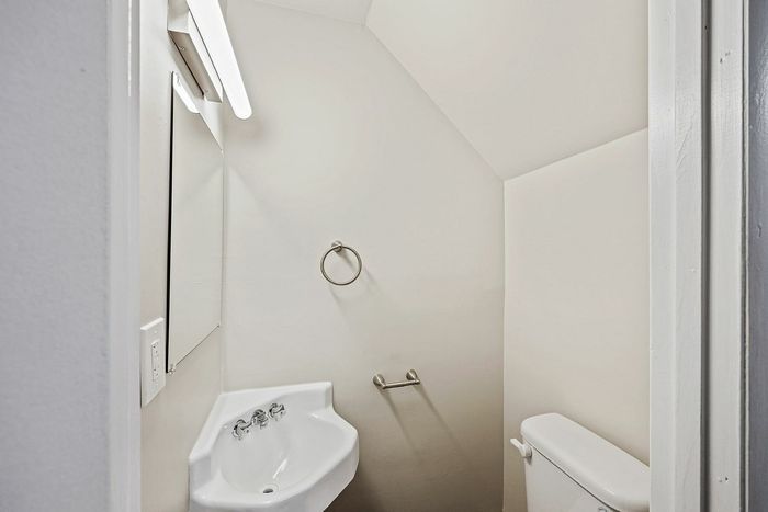Contemporary small bathroom with a sleek corner sink and minimalist fixtures.