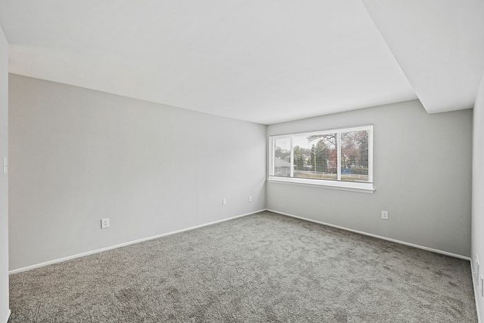 Bright, carpeted room with large window offering a scenic outdoor view.