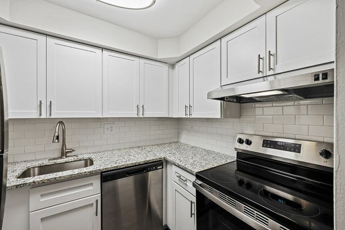 Sleek kitchen with granite countertops, stainless steel appliances, and white cabinetry.