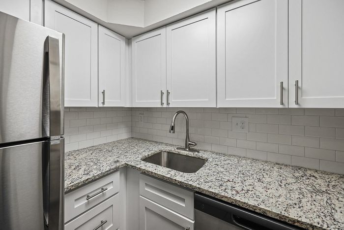 Modern kitchen with stainless steel appliances, granite countertops, and white cabinetry.
