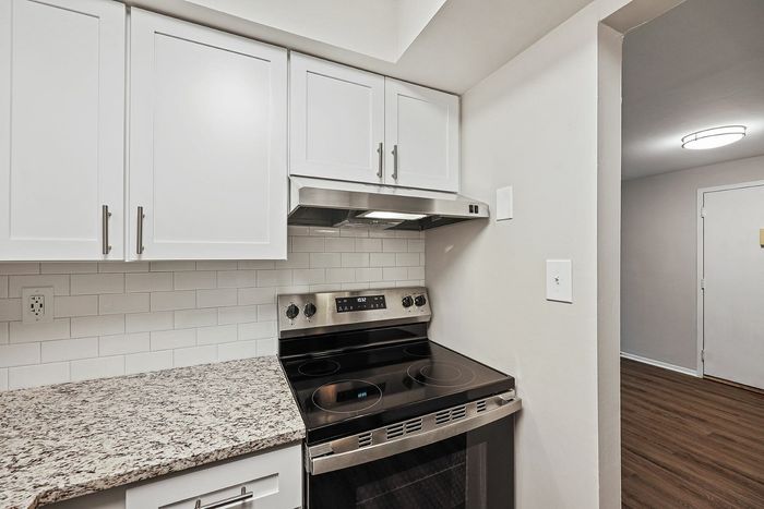 Modern kitchen with sleek white cabinets, granite countertops, and stainless steel appliances.
