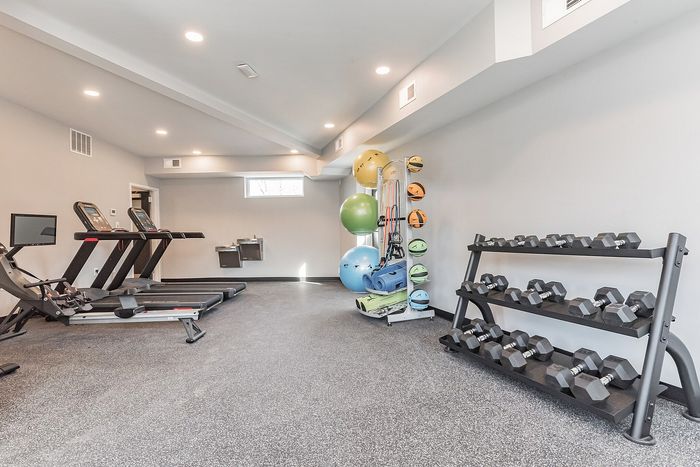 Sleek home gym equipped with treadmills, a set of dumbbells, and a variety of fitness gear.