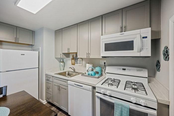 Modern kitchen with white appliances and wooden floors, highlighting the stylish interior of Townhomes at Rivers Gate.