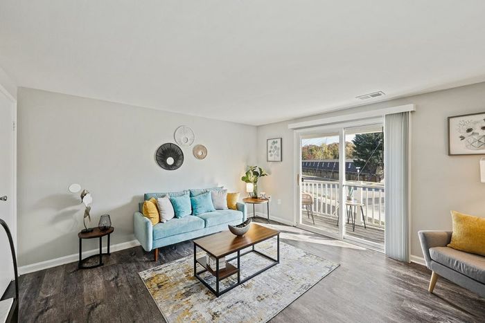 Stylish living room in Townhomes at Rivers Gate, showcasing hardwood floors and a sliding glass door for natural light.