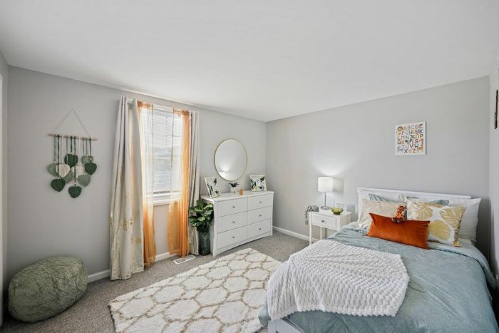 Bedroom in Townhomes at Rivers Gate showcasing a white dresser, a bed, and a window that adds warmth and light.