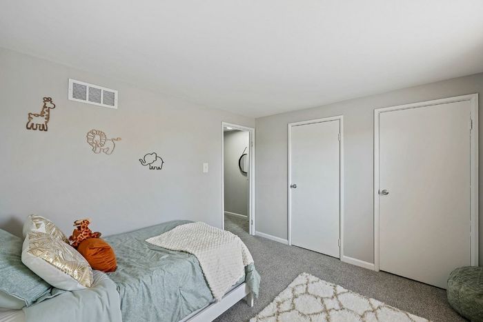 Inviting bedroom in Townhomes at Rivers Gate, showcasing a bed, dresser, and closet for stylish organization.