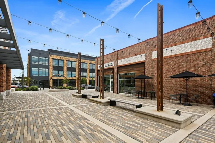 Vibrant outdoor plaza with modern brick architecture, trendy seating, and string lights for ambiance near Yard 56 Lofts.