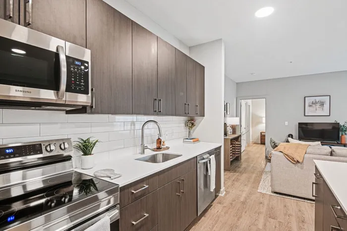 Contemporary kitchen with sleek cabinets and modern appliances, opening to bright, cozy living room at Yard 56 Lofts.