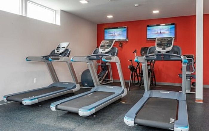 Modern fitness center with state-of-the-art treadmills and vibrant red accent wall.