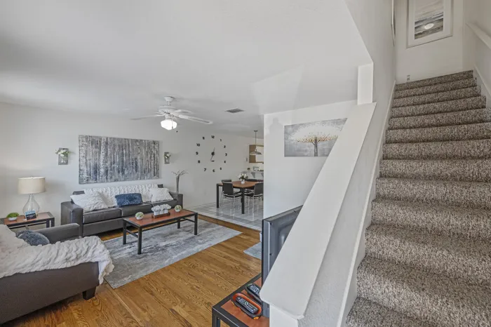 model unit staircase and living room. furnished the chairs, couches, coffee table, and tv stand.