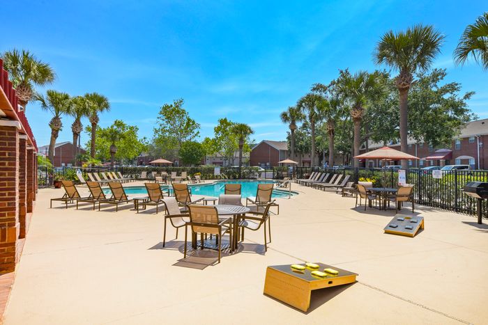 pool area with tables and chairs and cornhole