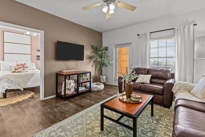 campus crossings at star pass model unit living room with couches, coffee table, tv stand, and wall mounted tv