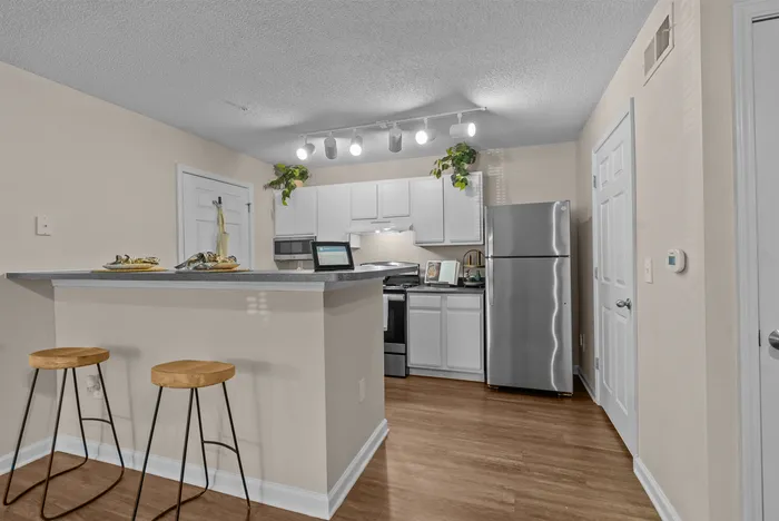 abbey west athens georgia model unit kitchen area with stainless steel refrigerator, stove/oven, and microwave.