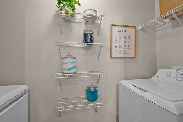 abbey west athens georgia model unit laundry room with washer, dryer, and jars of laundry soap, scent beads, and laundry pods.