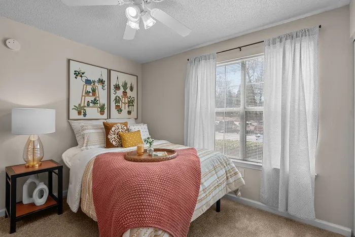 abbey west athens georgia model unit bedroom with queen sized bed, bedside table, and lamp.