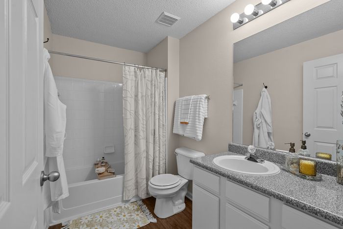 abbey west athens georgia model unit bathroom with full size tub/shower, toilet, and sink with granite countertop.