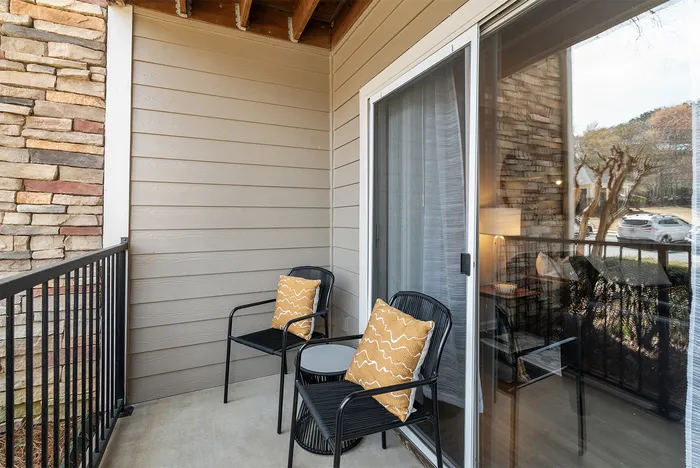 abbey west athens georgia model unit patio with two chairs and pillows, and small side table.