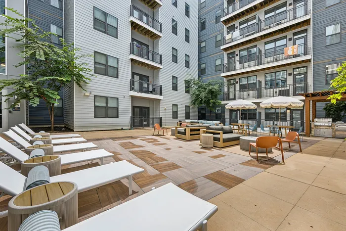 tenn student living knoxville exterior courtyard area with lounge seats. tables, umbrellas, and grills.
