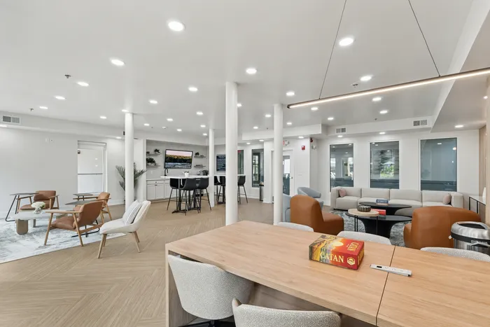 renovated resident lounge with long tables, tvs, and chairs.