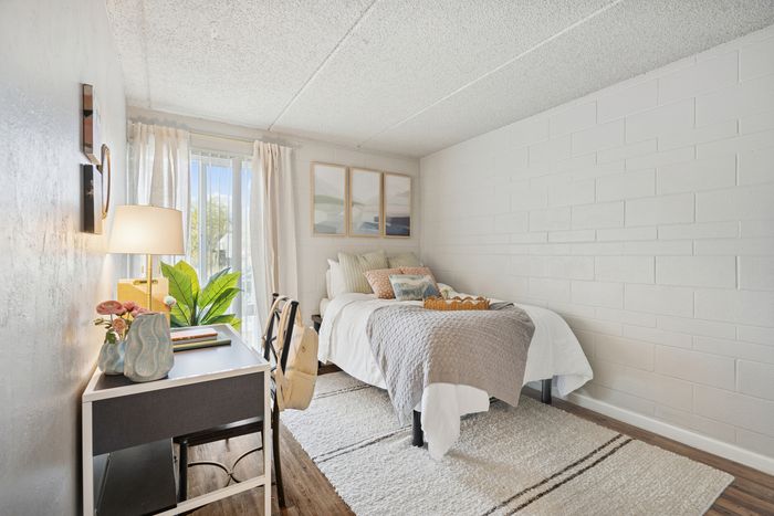 Bright and cozy bedroom with stylish decor, featuring a comfortable bed, elegant desk, and large window letting in natural light.