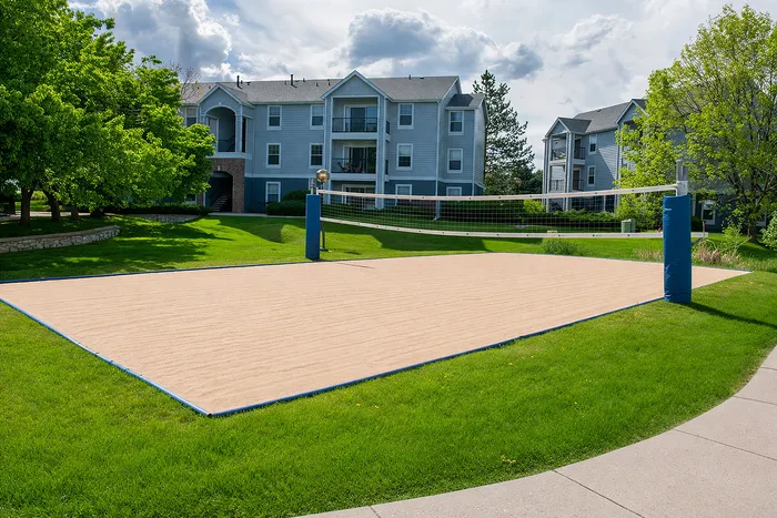 Charming apartment complex featuring a well-maintained sand volleyball court and lush green surroundings, perfect for an active lifestyle.
