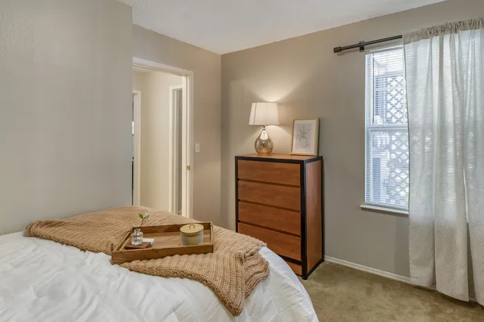 Cozy bedroom with soft lighting, elegant wooden dresser, and comforting luxury details, offering a warm and inviting atmosphere.