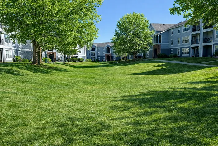 Peaceful apartment complex with lush green lawns and mature trees, offering a serene outdoor environment.