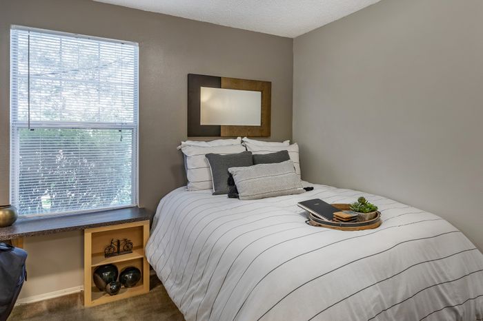 Cozy bedroom with elegant modern decor, featuring a comfortable bed, stylish cushions, and a large window providing natural light.