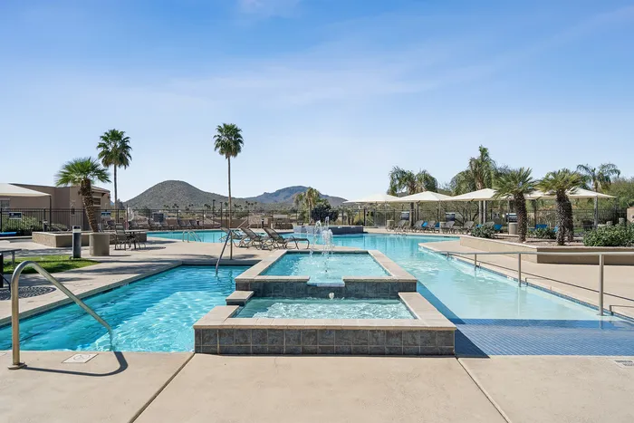 Luxurious resort-style pool area with fountain features, surrounded by palm trees and mountain views.